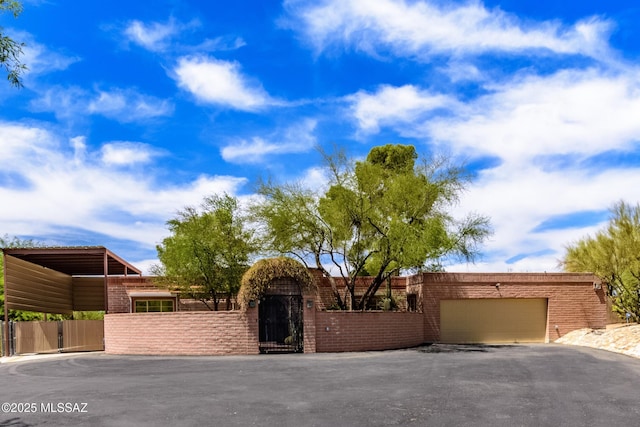 6945 N Mona Lisa Rd, Tucson, AZ 85741 - view of front facade with a fenced front yard, a garage, driveway, a gate, and brick siding