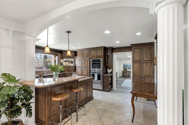 6945 N Mona Lisa Rd, Tucson, AZ 85741 - kitchen with appliances with stainless steel finishes, a warming drawer, arched walkways, ornate columns, and a breakfast bar area
