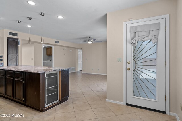941 W Fox Ridge Ln, Oro Valley, AZ 85737 - kitchen featuring independent washer and dryer, beverage cooler, baseboards, ceiling fan, and light stone counters