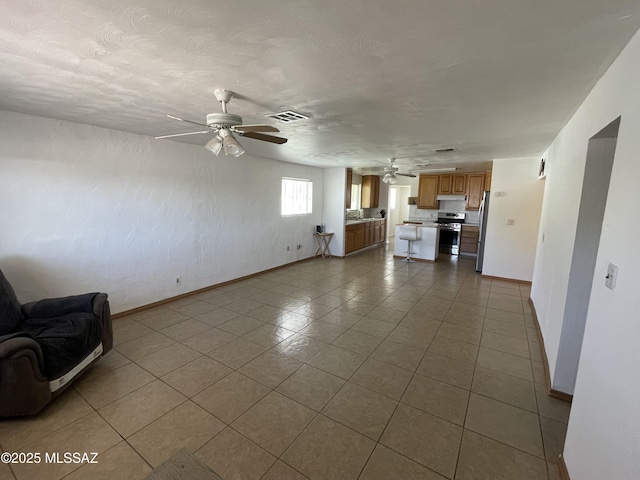 1202 E 26th St, Tucson, AZ 85713 - unfurnished living room featuring ceiling fan, baseboards, and dark tile patterned floors