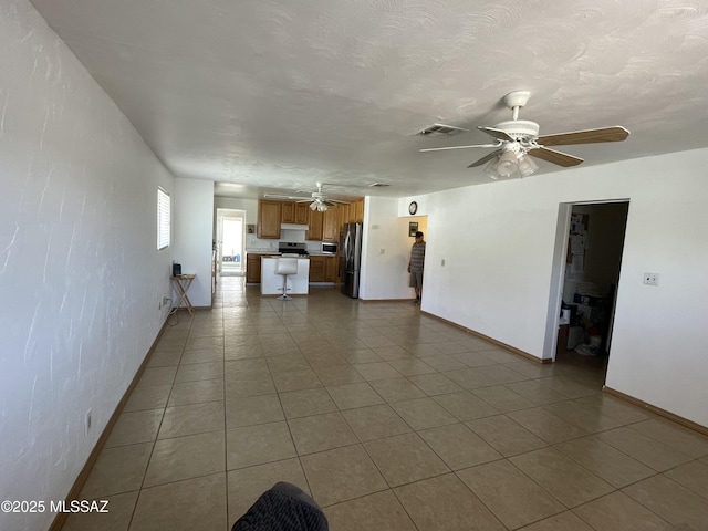 1202 E 26th St, Tucson, AZ 85713 - unfurnished living room with ceiling fan, baseboards, and dark tile patterned floors