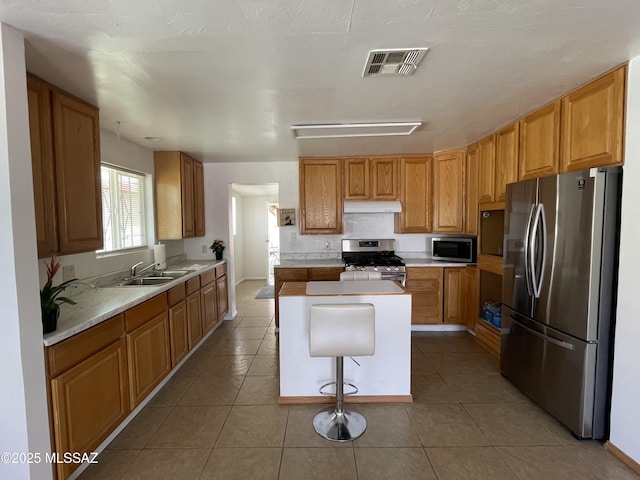 1202 E 26th St, Tucson, AZ 85713 - kitchen with stainless steel appliances, under cabinet range hood, a sink, a kitchen island, and light countertops
