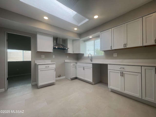 2330 N Los Altos Ave, Tucson, AZ 85705 - kitchen featuring wall chimney exhaust hood, a sink, baseboards, a skylight, and light countertops