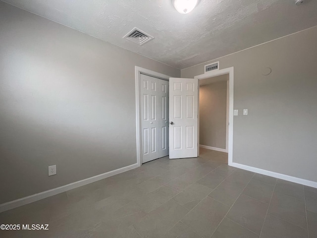 2330 N Los Altos Ave, Tucson, AZ 85705 - unfurnished bedroom featuring baseboards, a closet, a textured ceiling, and tile patterned flooring