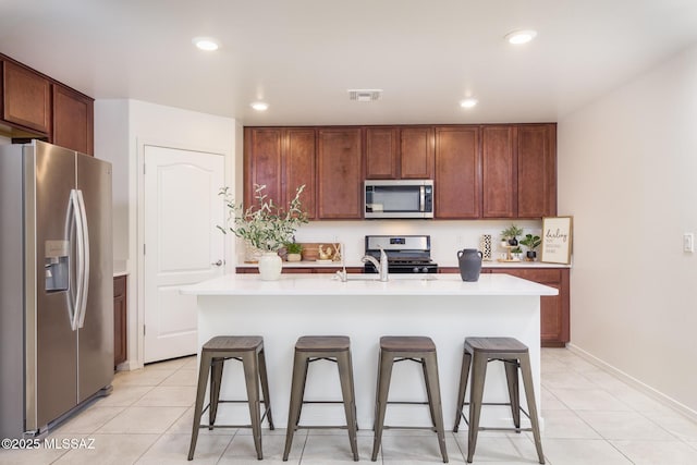 8608 N Genoa Ct, Tucson, AZ 85742 - kitchen with appliances with stainless steel finishes, a kitchen bar, light countertops, light tile patterned floors, and recessed lighting