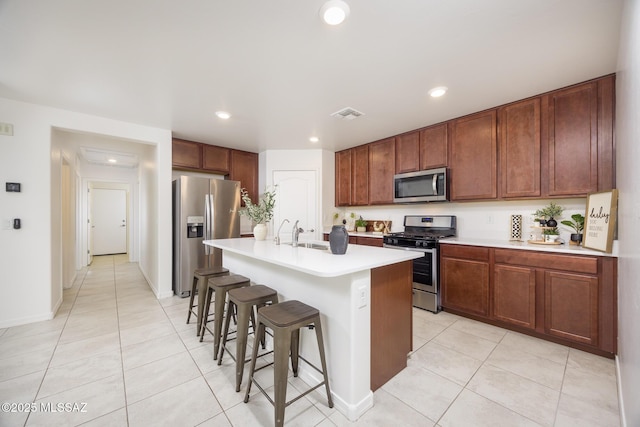 8608 N Genoa Ct, Tucson, AZ 85742 - kitchen with stainless steel appliances, a kitchen breakfast bar, light countertops, light tile patterned floors, and an island with sink