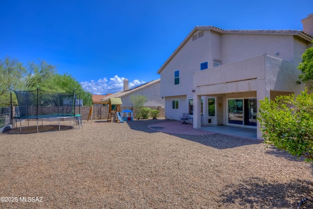 952 S Rincon Rising Rd, Tucson, AZ 85748 - back of house featuring a trampoline, a playground, a patio area, stucco siding, and a fenced backyard