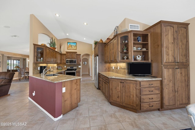 65535 E Rose Ridge Dr, Saddlebrooke, AZ 85739 - kitchen featuring appliances with stainless steel finishes, arched walkways, vaulted ceiling, light stone countertops, and backsplash