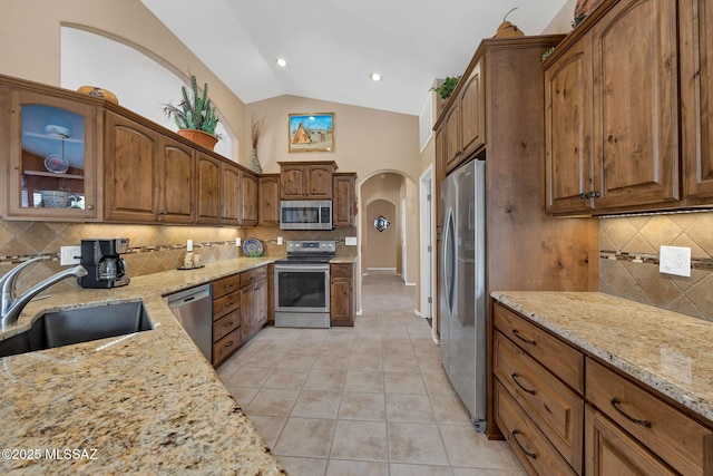 65535 E Rose Ridge Dr, Saddlebrooke, AZ 85739 - kitchen with stainless steel appliances, a sink, arched walkways, backsplash, and light stone counters