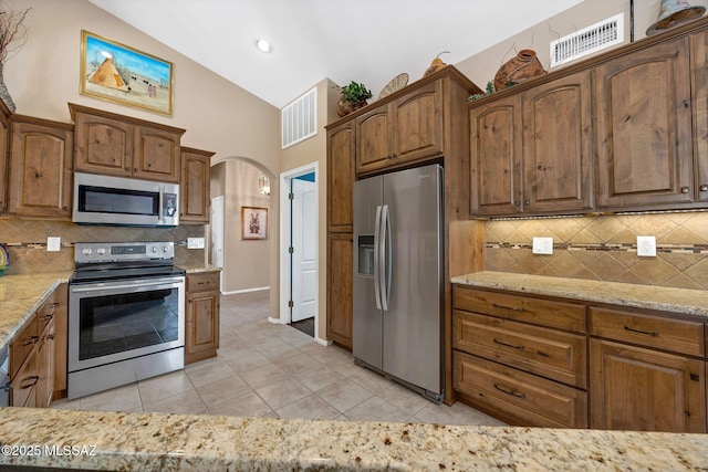 65535 E Rose Ridge Dr, Saddlebrooke, AZ 85739 - kitchen with appliances with stainless steel finishes, light tile patterned floors, light stone counters, tasteful backsplash, and high vaulted ceiling