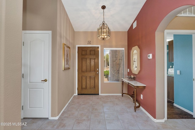 65535 E Rose Ridge Dr, Saddlebrooke, AZ 85739 - foyer entrance with arched walkways, light tile patterned floors, a chandelier, lofted ceiling, and baseboards