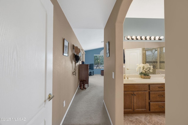 65535 E Rose Ridge Dr, Saddlebrooke, AZ 85739 - hallway with vaulted ceiling, light colored carpet, a sink, baseboards, and arched walkways