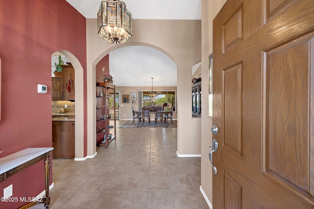 65535 E Rose Ridge Dr, Saddlebrooke, AZ 85739 - entryway featuring arched walkways, a chandelier, light tile patterned floors, baseboards, and a high ceiling