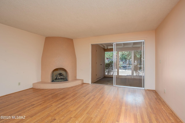4736 N Calle Lampara, Tucson, AZ 85718 - unfurnished living room featuring wood finished floors, a fireplace, and a textured ceiling