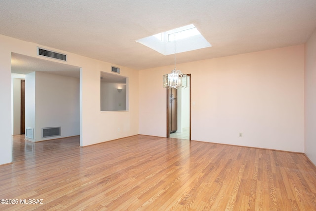 4736 N Calle Lampara, Tucson, AZ 85718 - unfurnished room featuring a skylight, a chandelier, and light wood finished floors