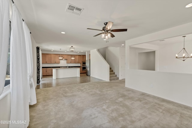 9569 N Sage Vista Ct, Tucson, AZ 85742 - unfurnished living room with recessed lighting, ceiling fan, a chandelier, stairs, and light carpet