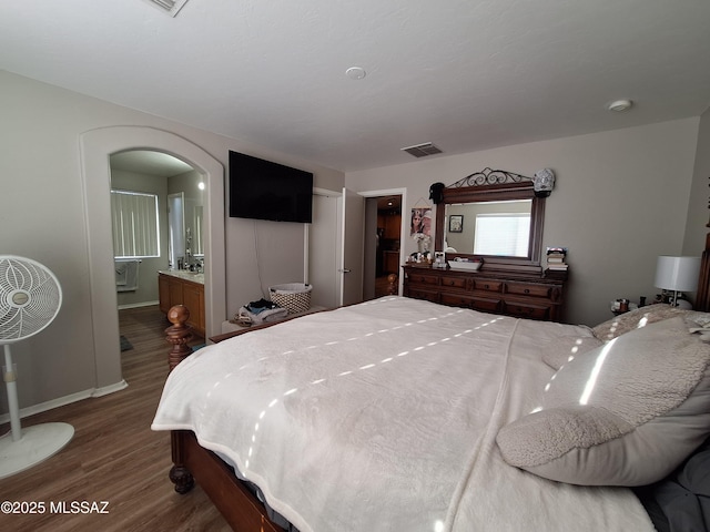 4396 S Valley Rd, Tucson, AZ 85714 - bedroom featuring wood finished floors, arched walkways, baseboards, and ensuite bath