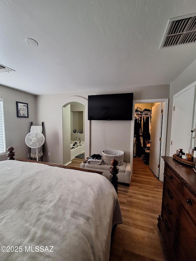 4396 S Valley Rd, Tucson, AZ 85714 - bedroom featuring arched walkways, wood finished floors, a walk in closet, and ensuite bathroom