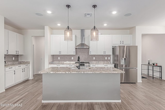 16800 S Paseo Las Vigas, Sahuarita, AZ 85629 - kitchen featuring wall chimney exhaust hood, stainless steel refrigerator with ice dispenser, decorative backsplash, light wood-type flooring, and white cabinetry