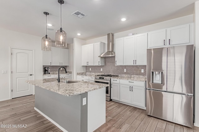 16800 S Paseo Las Vigas, Sahuarita, AZ 85629 - kitchen featuring appliances with stainless steel finishes, wall chimney exhaust hood, a sink, light wood-type flooring, and white cabinetry