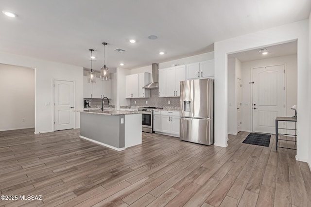 16800 S Paseo Las Vigas, Sahuarita, AZ 85629 - kitchen with appliances with stainless steel finishes, wall chimney exhaust hood, light wood-style flooring, white cabinets, and recessed lighting