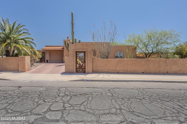 5457 S 13th Ave, Tucson, AZ 85706 - pueblo revival-style home featuring a fenced front yard, decorative driveway, an attached garage, and stucco siding