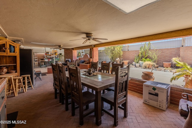5457 S 13th Ave, Tucson, AZ 85706 - dining area with brick flooring, a textured ceiling, a ceiling fan, and brick wall