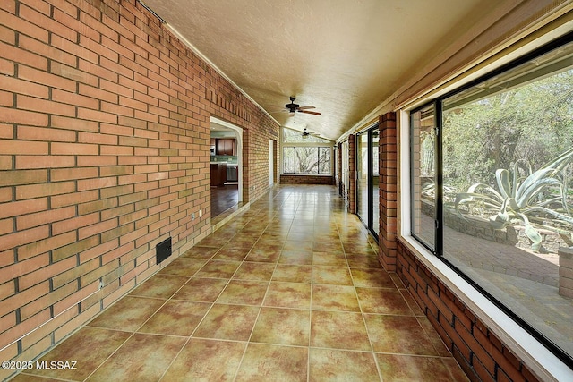 8932 N Rasmussen Ave, Tucson, AZ 85742 - hall featuring brick wall, a textured ceiling, tile patterned floors, and vaulted ceiling