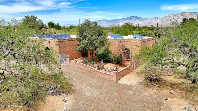 8932 N Rasmussen Ave, Tucson, AZ 85742 - view of front facade featuring solar panels, a mountain view, a chimney, and brick siding