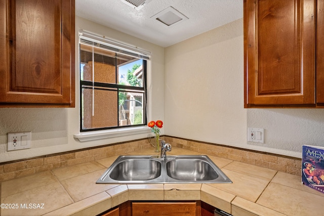 6651 N Campbell Ave Apt 221, Tucson, AZ 85718 - kitchen with a sink, light countertops, brown cabinets, and a textured wall