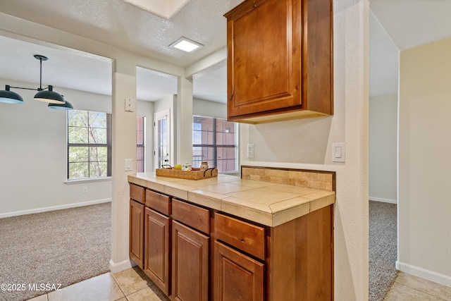 6651 N Campbell Ave Apt 221, Tucson, AZ 85718 - kitchen featuring light carpet, brown cabinetry, tile countertops, and baseboards