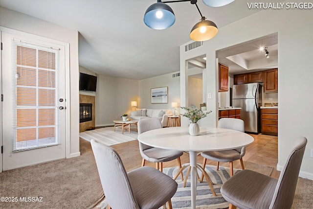 6651 N Campbell Ave Apt 221, Tucson, AZ 85718 - dining room featuring a glass covered fireplace, a raised ceiling, light colored carpet, and baseboards