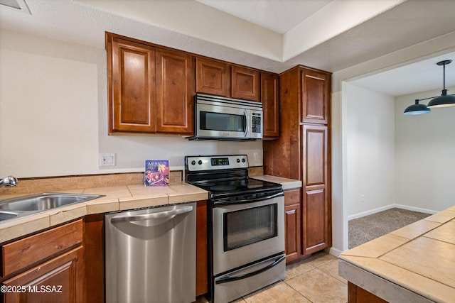 6651 N Campbell Ave Apt 221, Tucson, AZ 85718 - kitchen featuring appliances with stainless steel finishes, a sink, tile counters, brown cabinetry, and decorative light fixtures