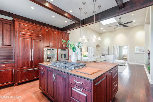 3750 E Sumo Quinto, Tucson, AZ 85718 - kitchen with stainless steel appliances, beamed ceiling, ceiling fan, a kitchen island, and dark brown cabinets
