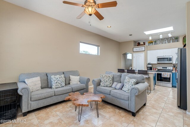 7511 W Sweet River Rd, Tucson, AZ 85743 - living room with arched walkways, light tile patterned flooring, a skylight, and ceiling fan