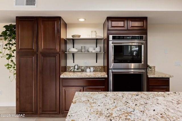 8628 N Placita Del Cardo, Tucson, AZ 85704 - kitchen with stainless steel double oven, dark brown cabinets, and light stone counters