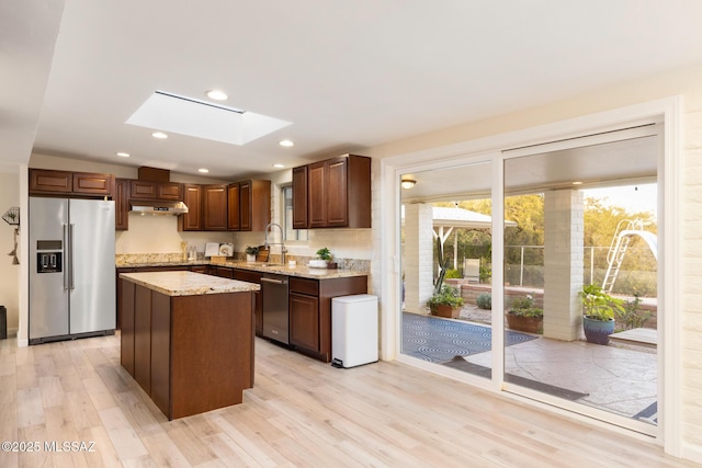 8628 N Placita Del Cardo, Tucson, AZ 85704 - kitchen featuring stainless steel appliances, a skylight, under cabinet range hood, light wood-style flooring, and a sink