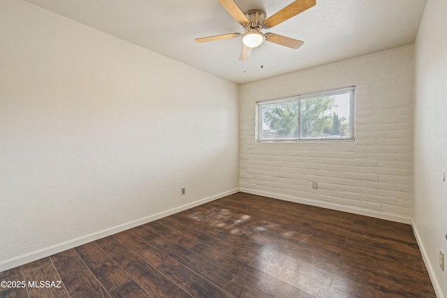 1716 S Sleepy Hollow Ave, Tucson, AZ 85710 - spare room featuring dark wood-style flooring, baseboards, ceiling fan, and brick wall
