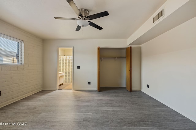 1716 S Sleepy Hollow Ave, Tucson, AZ 85710 - unfurnished bedroom featuring wood finished floors, baseboards, brick wall, a closet, and ceiling fan