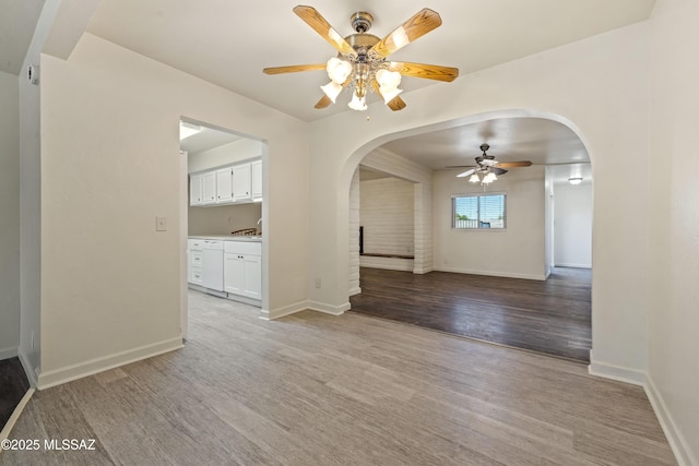 1716 S Sleepy Hollow Ave, Tucson, AZ 85710 - unfurnished dining area with arched walkways, a ceiling fan, wood finished floors, and baseboards