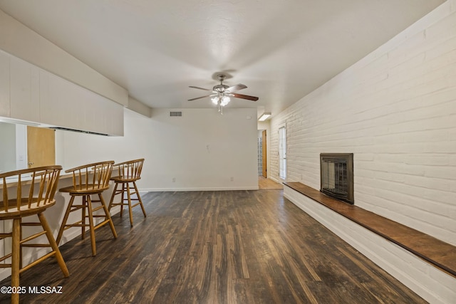 1716 S Sleepy Hollow Ave, Tucson, AZ 85710 - living area with wood finished floors, ceiling fan, a brick fireplace, baseboards, and brick wall