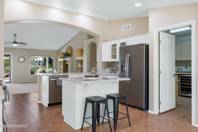37358 S Ridgeview Blvd, Saddlebrooke, AZ 85739 - kitchen with appliances with stainless steel finishes, beverage cooler, a peninsula, lofted ceiling, and white cabinets