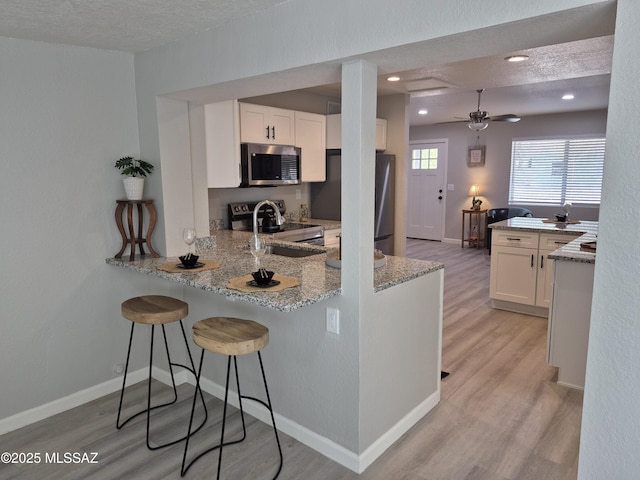 230 N Biddle Ave, Willcox, AZ 85643 - kitchen featuring appliances with stainless steel finishes, a peninsula, light wood-style floors, a sink, and a textured ceiling
