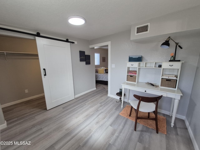 230 N Biddle Ave, Willcox, AZ 85643 - home office featuring a barn door, wood finished floors, baseboards, and a textured ceiling