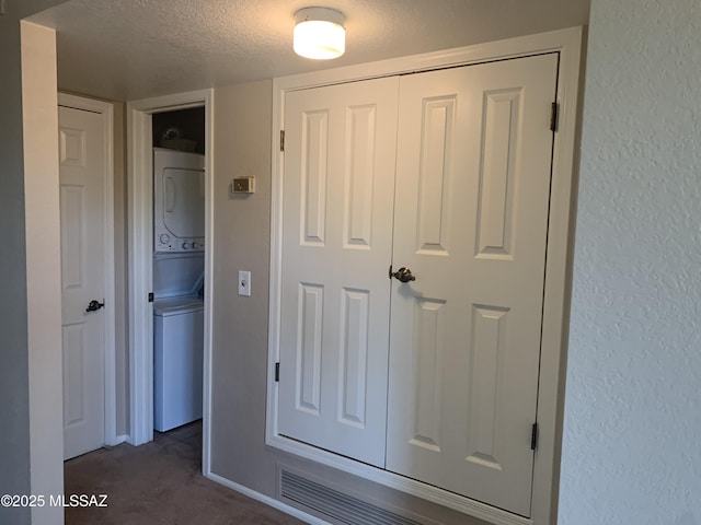 8271 N Oracle Rd Unit 146, Tucson, AZ 85704 - unfurnished bedroom with stacked washer / dryer, a textured ceiling, a textured wall, dark colored carpet, and a closet