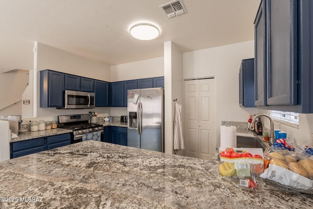 13218 E Mineta Ridge Dr, Vail, AZ 85641 - kitchen featuring appliances with stainless steel finishes, light stone counters, a peninsula, and blue cabinetry