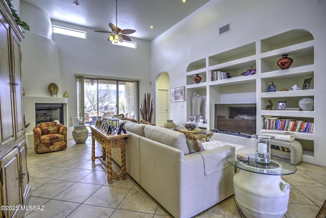 2460 N Cavalry Trl, Tucson, AZ 85749 - living room with ceiling fan, arched walkways, a high ceiling, a fireplace, and light tile patterned flooring