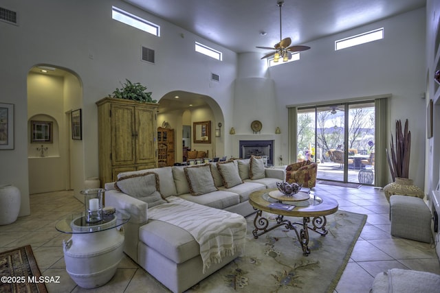 2460 N Cavalry Trl, Tucson, AZ 85749 - living area with a ceiling fan, light tile patterned flooring, arched walkways, a high ceiling, and a fireplace