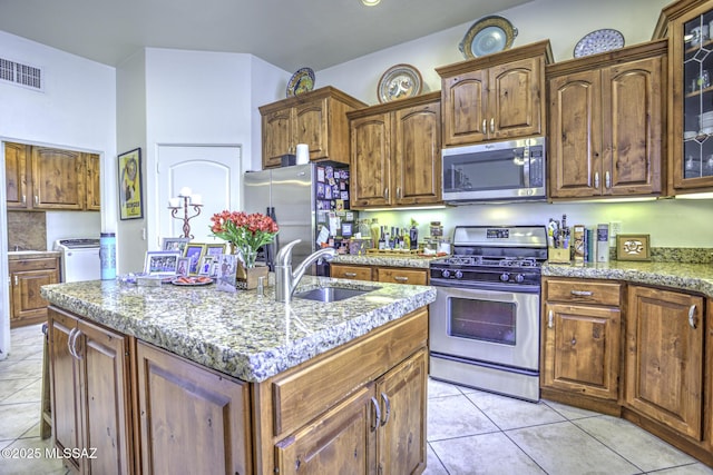 2460 N Cavalry Trl, Tucson, AZ 85749 - kitchen with stainless steel appliances, a sink, glass insert cabinets, light stone counters, and a center island with sink