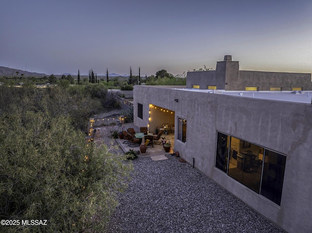 2460 N Cavalry Trl, Tucson, AZ 85749 - back of property at dusk featuring a patio and stucco siding